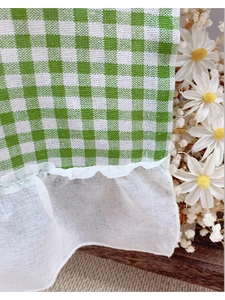 Detail of green plaid cafe curtain with delicate white lace ruffle and daisy decor