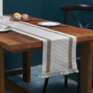 Bohemian linen table runner with brown woven stripes and tassels on a wooden table