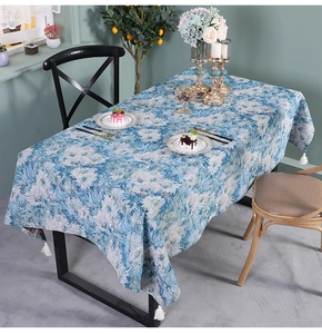 Close-up of blue floral table runner with decorative white cotton corner tassels