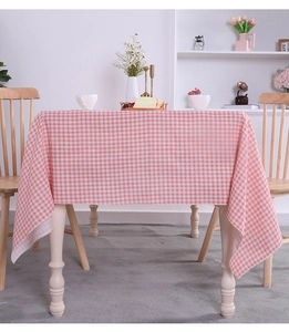 Detailed view of a pink and white gingham cotton linen tablecloth on a dining table