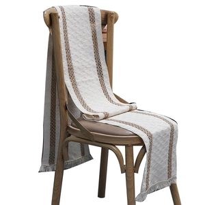 Two-tone woven cotton linen table runner with tassels draped over a vintage wooden chair