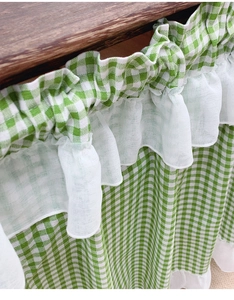 Detail view of green plaid cafe curtain with elegant white lace ruffles on wood beam