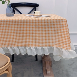 Yellow and white gingham tablecloth with ruffled edges in a cozy dining setting