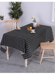 Close-up detail of the black and white checkered linen tablecloth on a wooden dining table