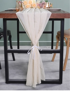 Detailopname van beige chiffon tafelloper met fijne geplooide textuur en elegante witte linten