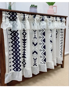 Detail of bohemian cafe curtain featuring ethnic geometric prints and delicate lace hem