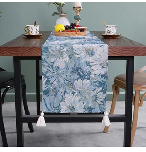 Close-up of retro blue and white floral jacquard table runner with decorative white tassels