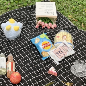 Classic black and white checkered outdoor picnic mat on grass with snack props