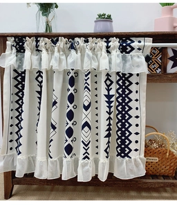 Detail of bohemian cafe curtain with navy geometric patterns and white lace trim