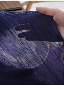 Detail van de marineblauwe geplooide tafelloper met transparante stof en goudpatronen
