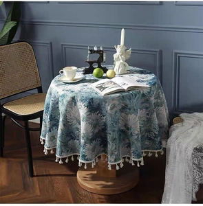 Detailed close-up of blue floral tablecloth featuring off-white tassel fringe edges