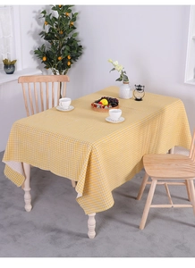 Detail of yellow and white checkered cotton linen tablecloth on a wooden table