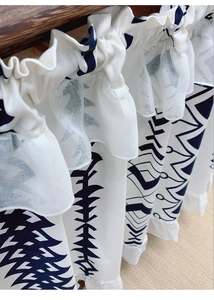 Detail of bohemian café curtain featuring blue geometric patterns and double ruffled edges