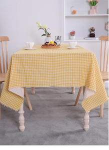 Detailed texture of yellow and white checkered cotton linen tablecloth on a wooden table