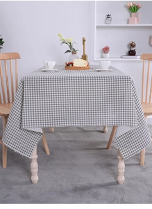 Detailed close-up of grey and white checkered linen tablecloth on a cozy wooden dining table