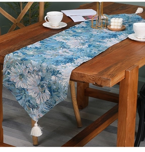 Detailed close-up of blue table runner featuring white floral jacquard and cotton tassels