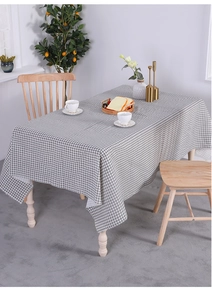Close-up of grey and white checkered linen tablecloth draped on a wooden dining table