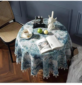 Detailed view of teal floral jacquard round tablecloth with decorative white tassel fringe
