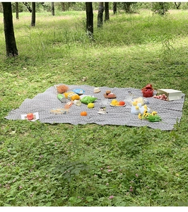 Outdoor gray picnic mat with white geometric patterns displayed on a green lawn