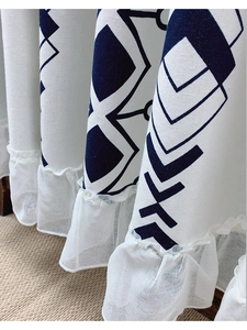 Close-up of linen fabric with blue geometric patterns and white ruffled edge detail