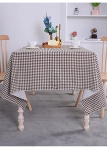 Detailed close-up of brown and white checkered cotton linen tablecloth with frayed edges