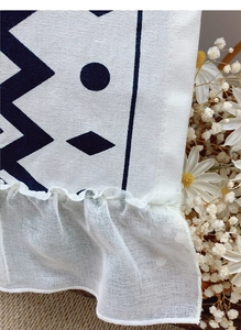 Close-up of bohemian cafe curtain with geometric pattern and delicate white lace trim