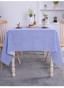Detail of blue and white checkered linen tablecloth with natural drape on wooden table