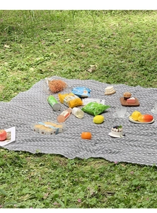 Close-up of gray herringbone picnic mat on green grass for outdoor camping