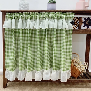 Green gingham cafe curtain with white ruffle lace edges displayed on a wooden shelf