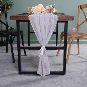 Grijze geplooide chiffon tafelloper met wit lint op een houten eettafel
