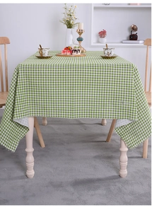 Close-up of a green and white checkered cotton linen tablecloth on a wooden dining table