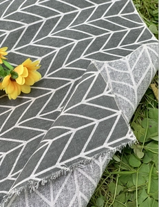Detailed view of gray geometric woven picnic mat showing texture on green grass