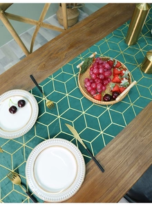Vue détaillée du chemin de table en velours vert foncé avec motifs géométriques dorés
