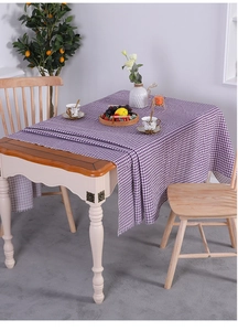 Detailed close-up of purple plaid linen tablecloth with fringed edges on wooden table