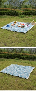 Detailed view of a bohemian style floral picnic mat with fringe edges on a natural green lawn
