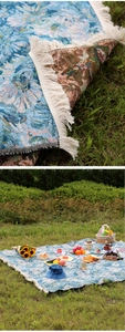 Detail of Bohemian floral woven picnic mat featuring white tassels on a grassy field