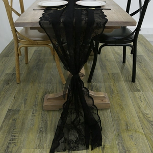 Elegant black lace table runner with hollow floral pattern and satin bow decoration