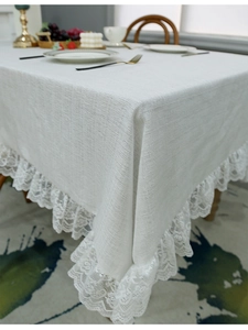 Close-up of elegant white lace border detail on a textured linen tablecloth