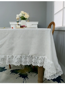 Detail of elegant linen tablecloth with scalloped lace edge on a wooden table