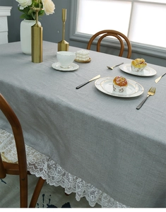 Detailansicht der hellgrauen Leinentischdecke mit breiter weißer Vintage-Spitze