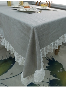 Detailaufnahme der grauen Leinentischdecke mit eleganter weißer Spitze und rustikaler Textur