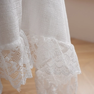 Detail of white linen tablecloth featuring delicate floral lace trim and fabric texture