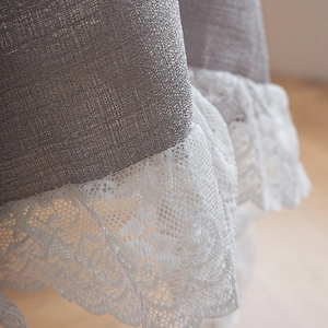 Detailed close-up of grey linen fabric and delicate white lace trim on the tablecloth