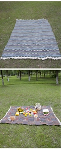 Detailed view of a bohemian style picnic blanket with fringe on lush green grass