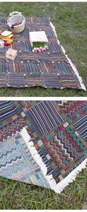 Detailed view of Bohemian ethnic style woven picnic blanket with white fringe on grass