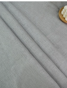 Detail der grauen Leinentischdecke mit feiner Webstruktur und nordischem Fransenrand