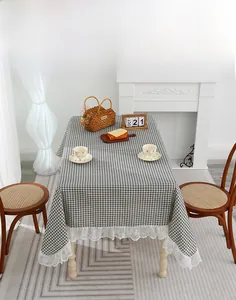 Close-up of grey plaid cotton linen tablecloth with delicate white lace edge in a dining room