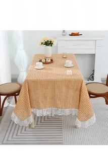 Detail of orange checkered cotton linen tablecloth with elegant white lace edge trim