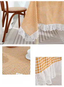 Detail of yellow checkered cotton linen tablecloth with elegant white lace embroidery