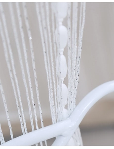 Close-up of white fringe curtain with silver sequins and decorative olive beads